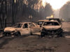 Burned cars are seen on a local road during a forest fire near Pedrogao Grande