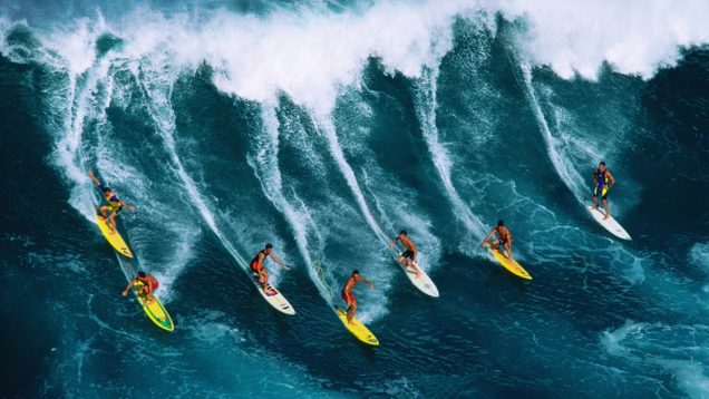 Seven surfers riding large wave, Hawaii, USA, aerial view