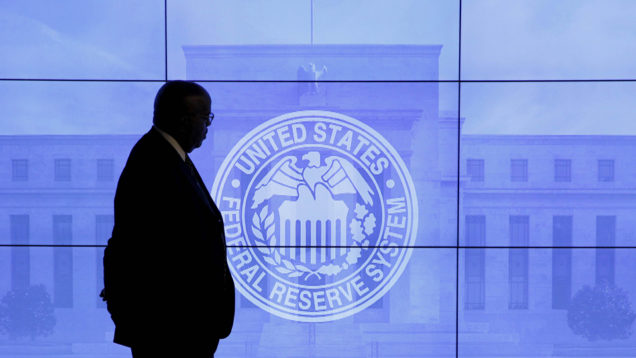 A guard walks in front of a Federal Reserve image before press conference in Washington